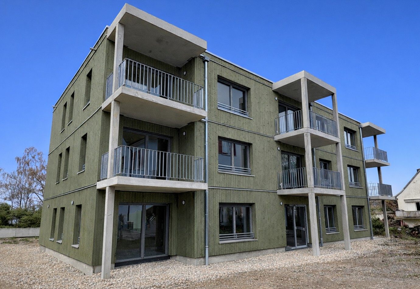 Wohnbau Gottmadingen, Otto-Dix-Straße – grüne Holzfassade mit vorgestellten Betonbalkonen