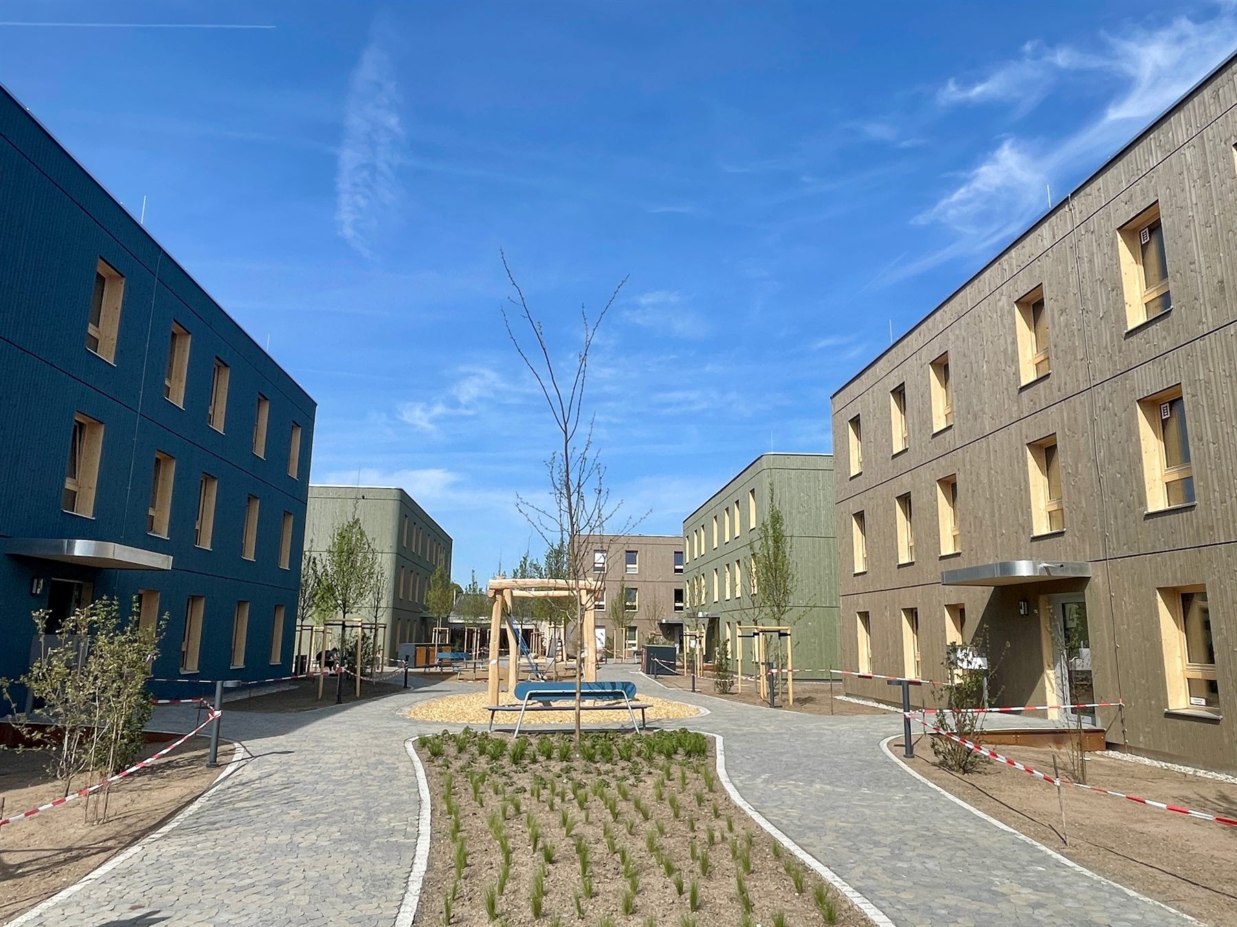 WoodRocks Wohnquartier Mannheim – fünf Holzmodulgebäude mit farbigen Holzfassaden um einen begrünten Innenhof