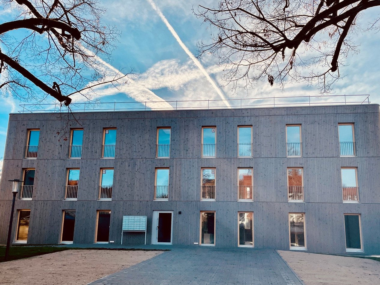 Wohnbau Metzingen, Fliederstraße: dreigeschossiger Holzbau mit heller vertikaler Schalung, bodentiefen Fenstern und Briefkastenanlage am Eingang